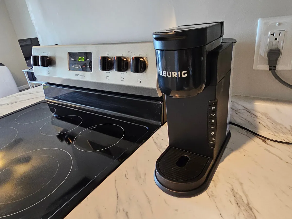 A modern kitchen space equipped with a Keurig coffee maker, stove, and marble countertop. The area invites socializing over breakfast or coffee, combining practicality with a warm, inviting atmosphere.